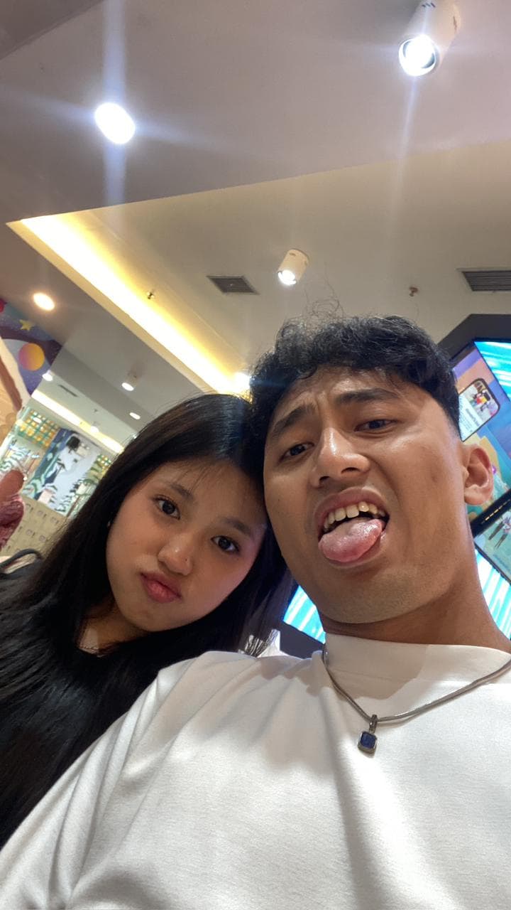 Nayla dan pasangannya membuat ekspresi playful dalam selfie di arcade.